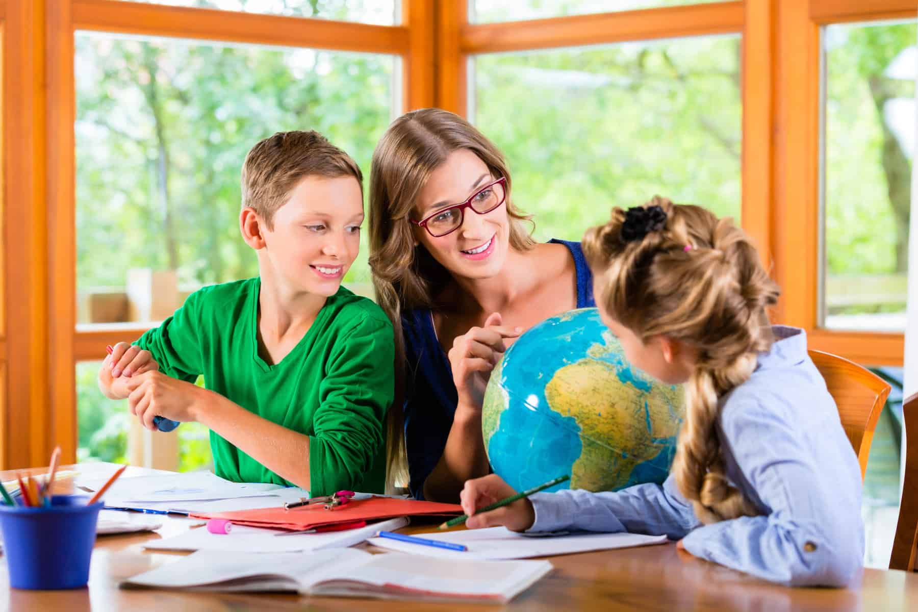 Homeschool students examining a globe in accordance with their state's homeschool laws