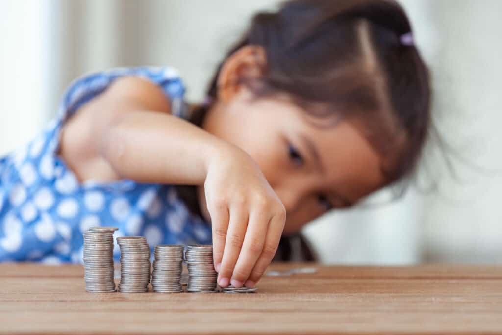 A student playing with coins to organically learn about money as part of her unschooling education