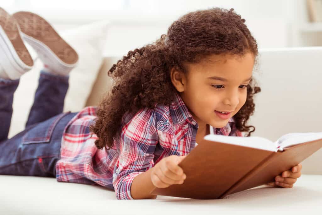Child reading a book as they learn with the Charlotte Mason homeschooling method.