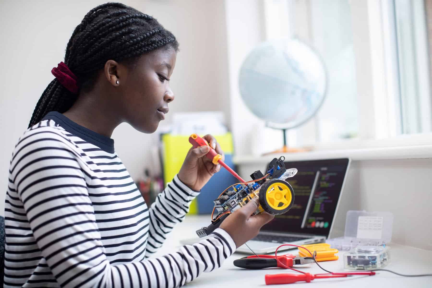 Female student building a robotic car for a science project.