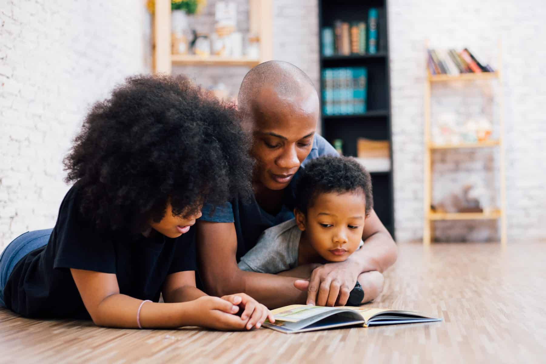 African American father reading a book to his two young children