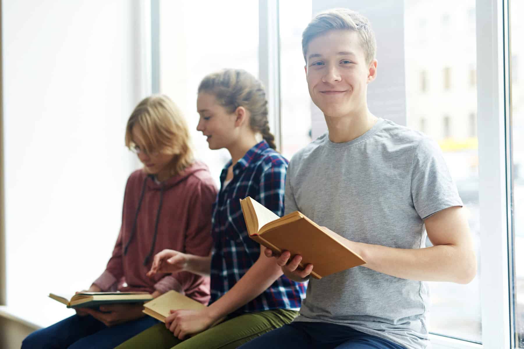 High school student reading a book with friends