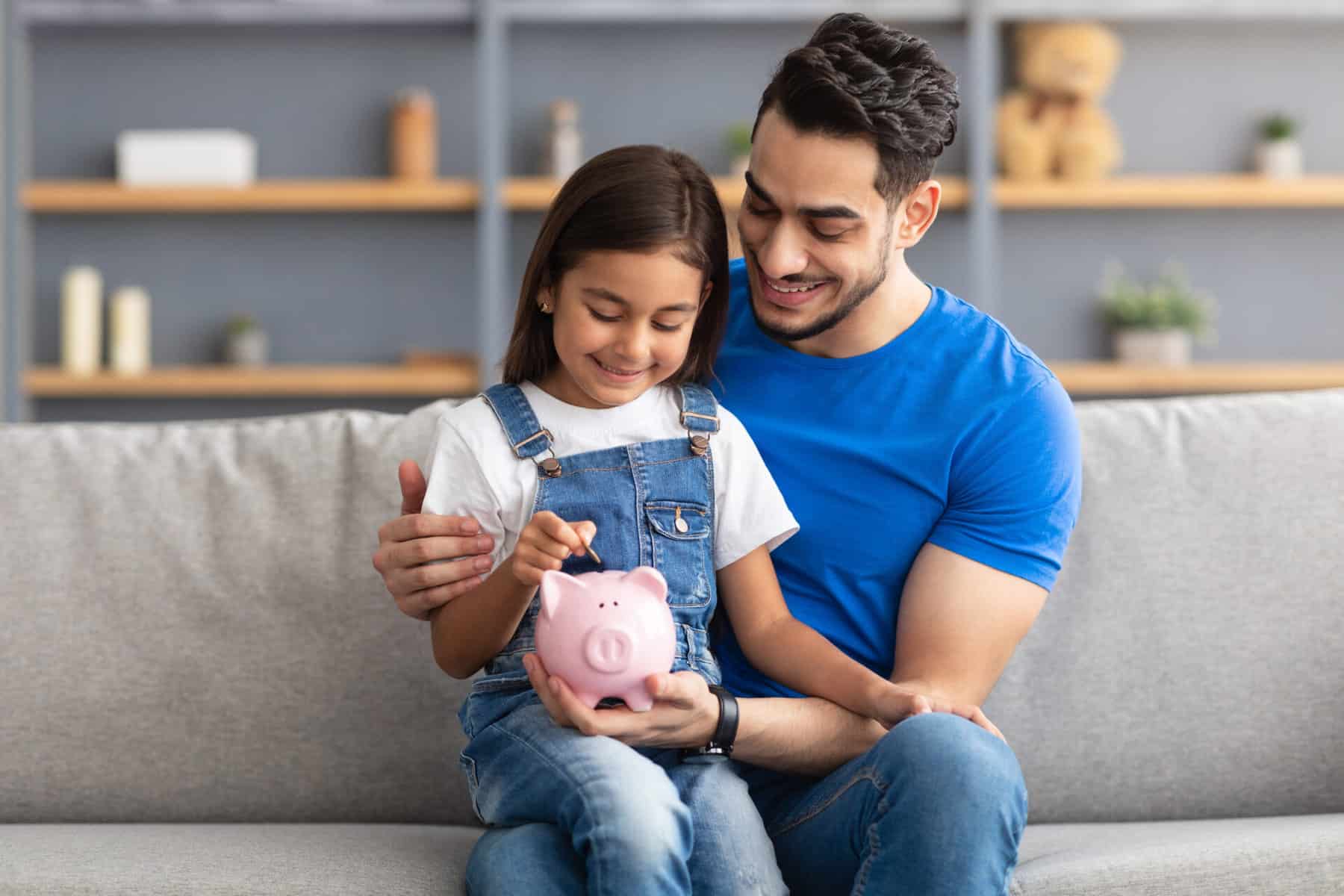 Dad and daughter filling a piggy bank with coins