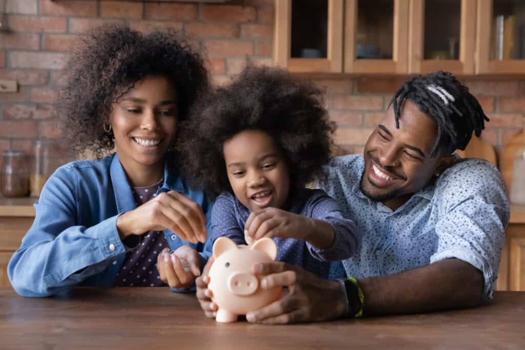 African american family adding coins to a piggy bank