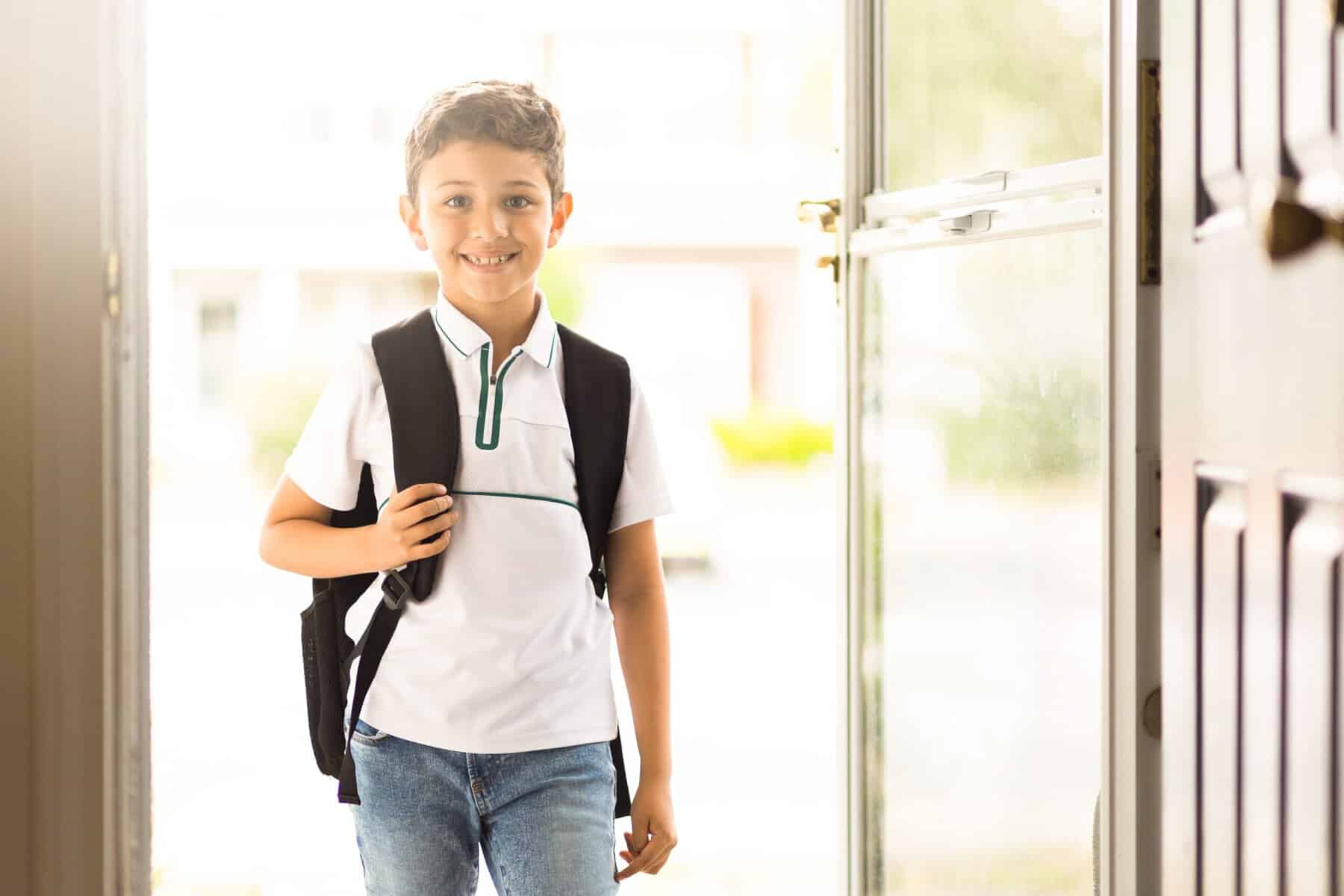 Boy coming home from school wearing his backpack