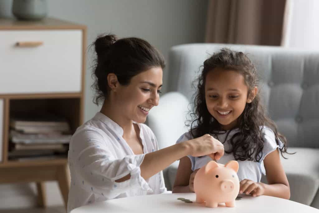 Mother and daughter put coins into a piggy bank