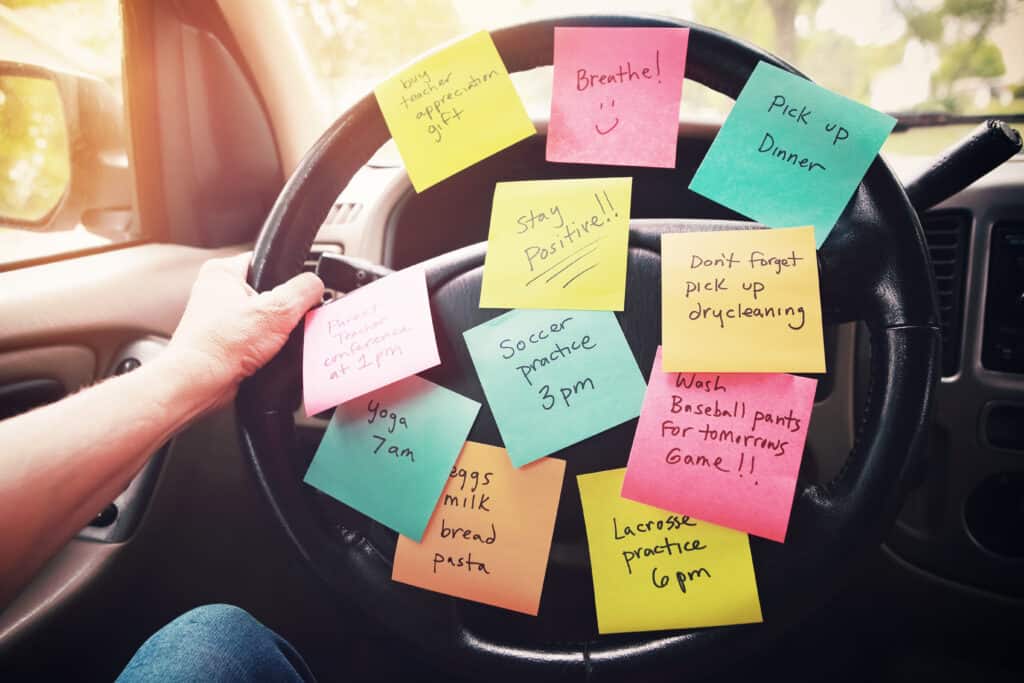 Steering wheel covered in sticky notes with reminders on them