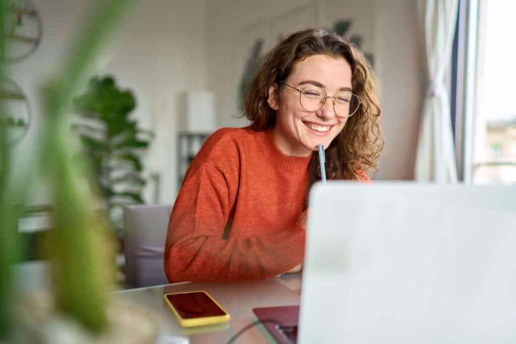Young woman with curly hair using her laptop for homework