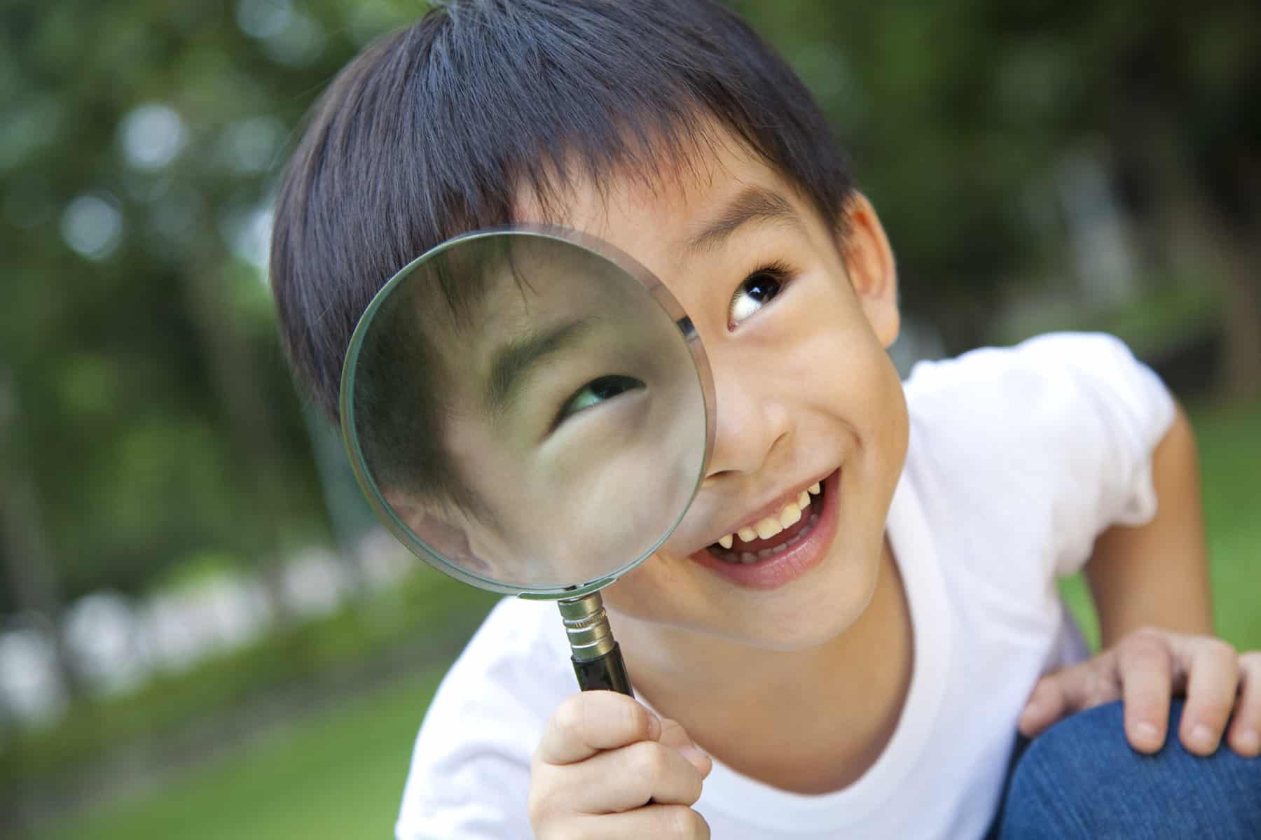 Asian boy holding a magnifying glass