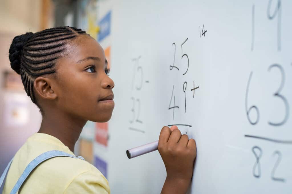 Young Black girl doing double digit addition on a whiteboard