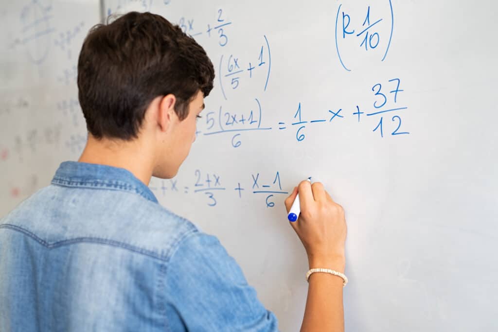 Boy doing algebra on a whiteboard