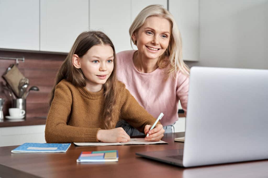 Mom and daughter using a laptop together and smiling