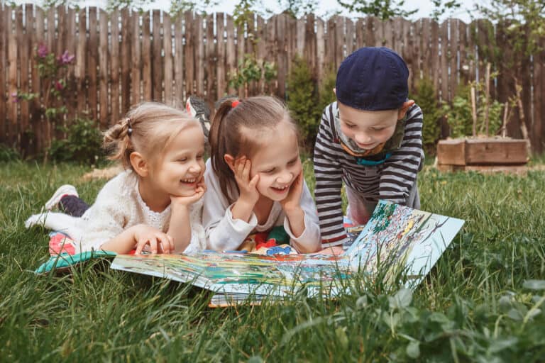 Three children laying in the grass looking at a map