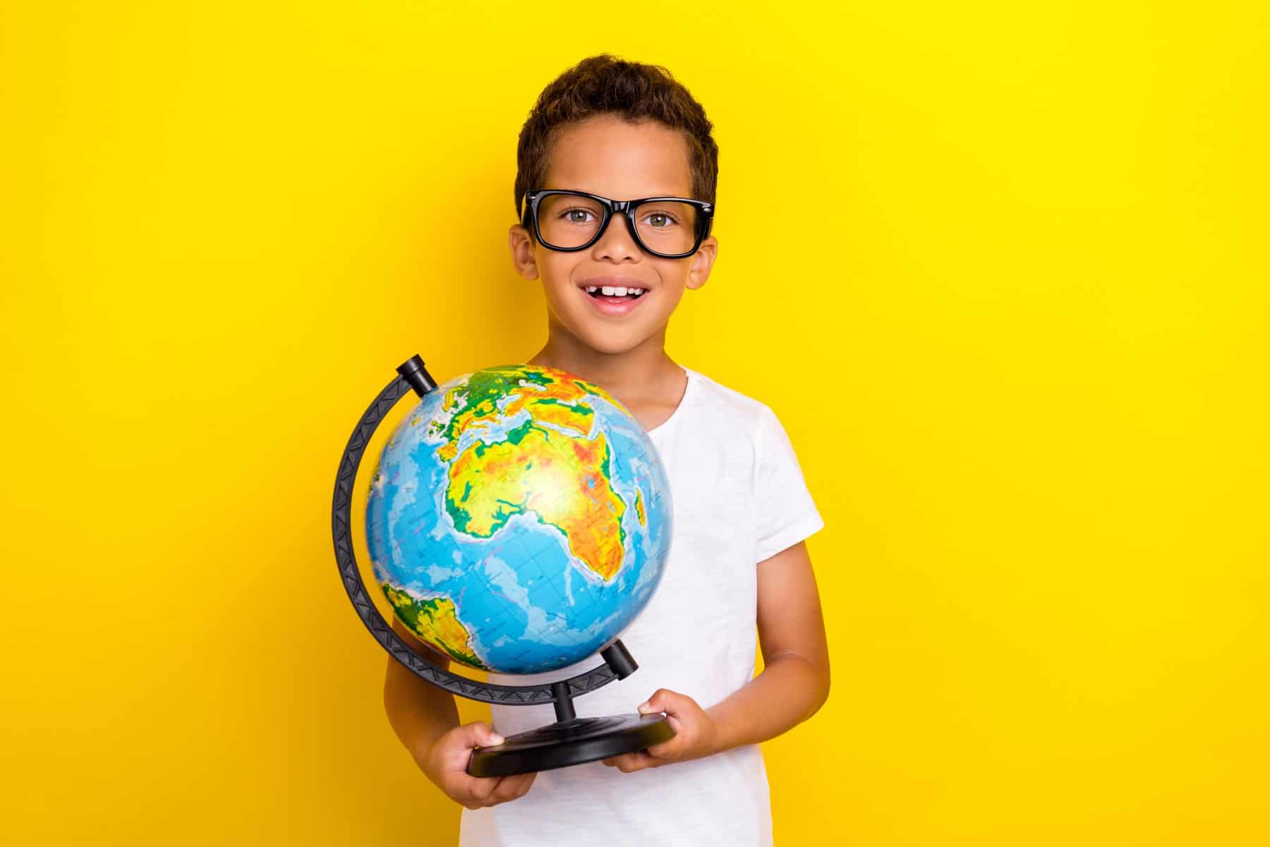 Young boy with glasses holding a globe