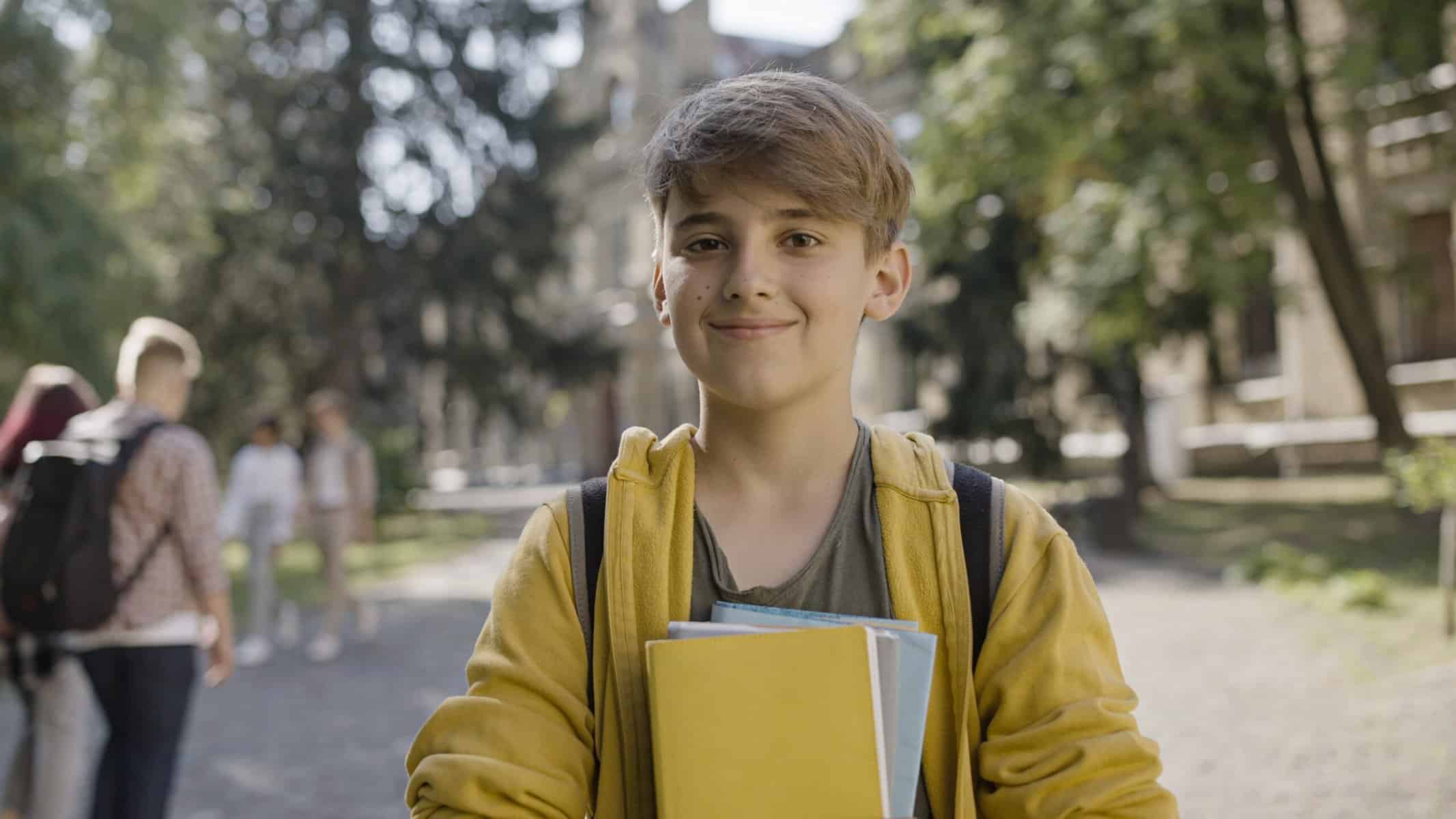 Middle school boy holding a notebook and smiling