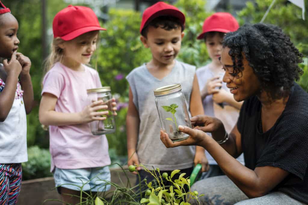 Woman showing kids on a field trip a plant in a jar