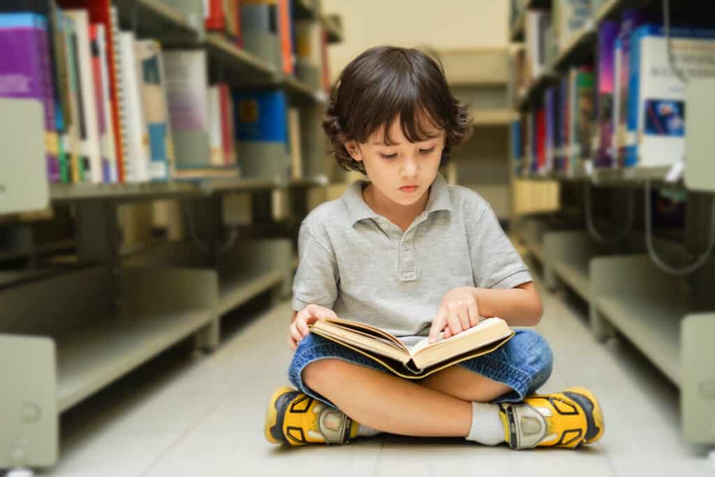 Boy sitting down and reading in a library