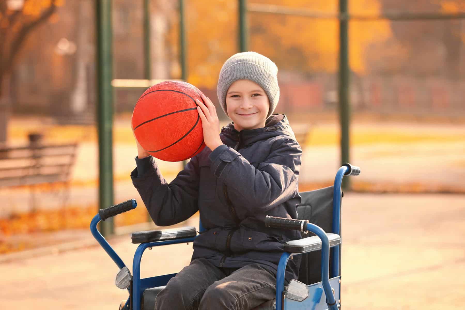 Little boy in a wheelchair holding a basketball
