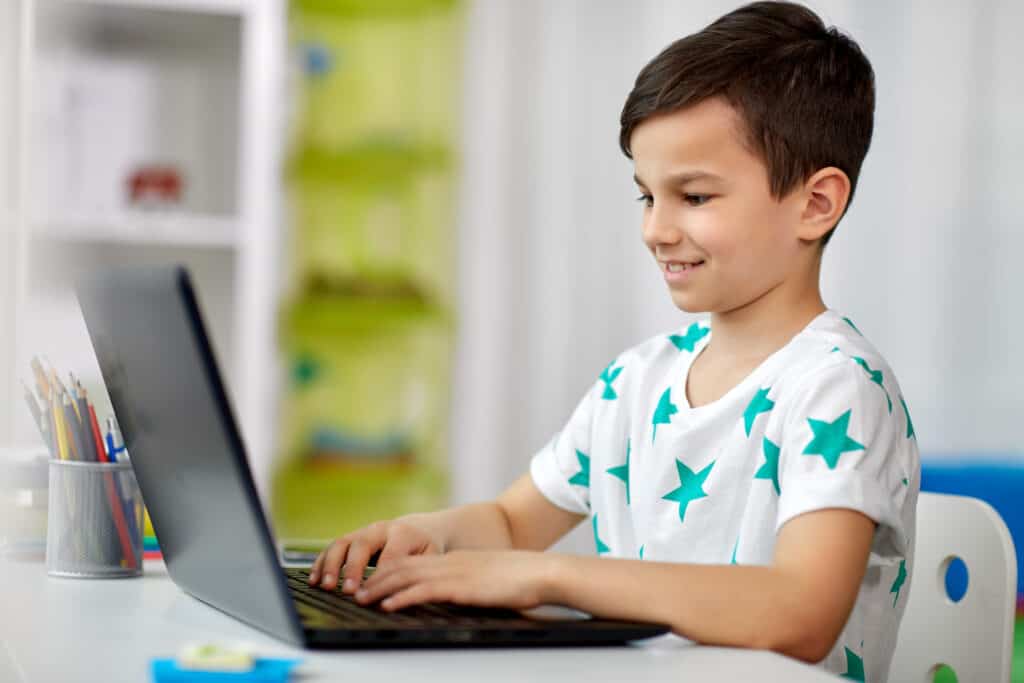 Little boy smiling at a laptop