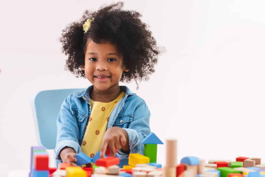 Little girl playing with colorful blocks at a table