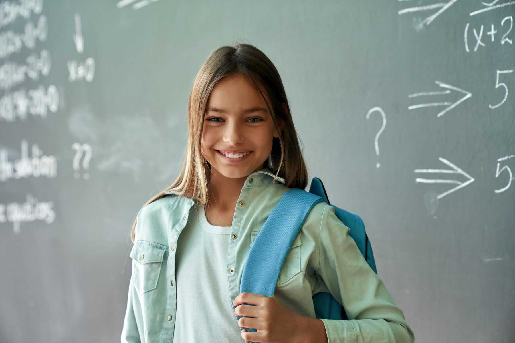 Young girl smiling in front of a blackboard