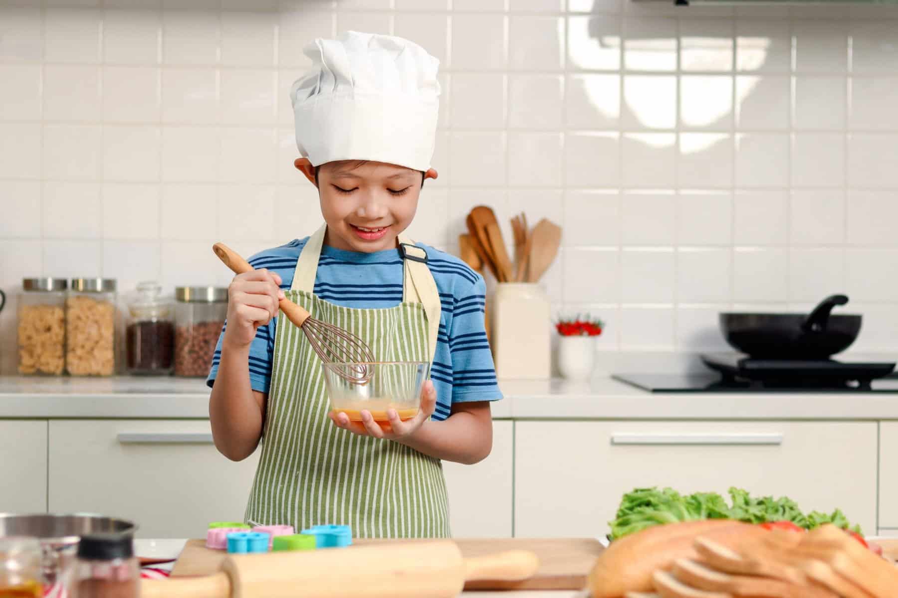 Little boy wearing a chef's hat holding a bowl
