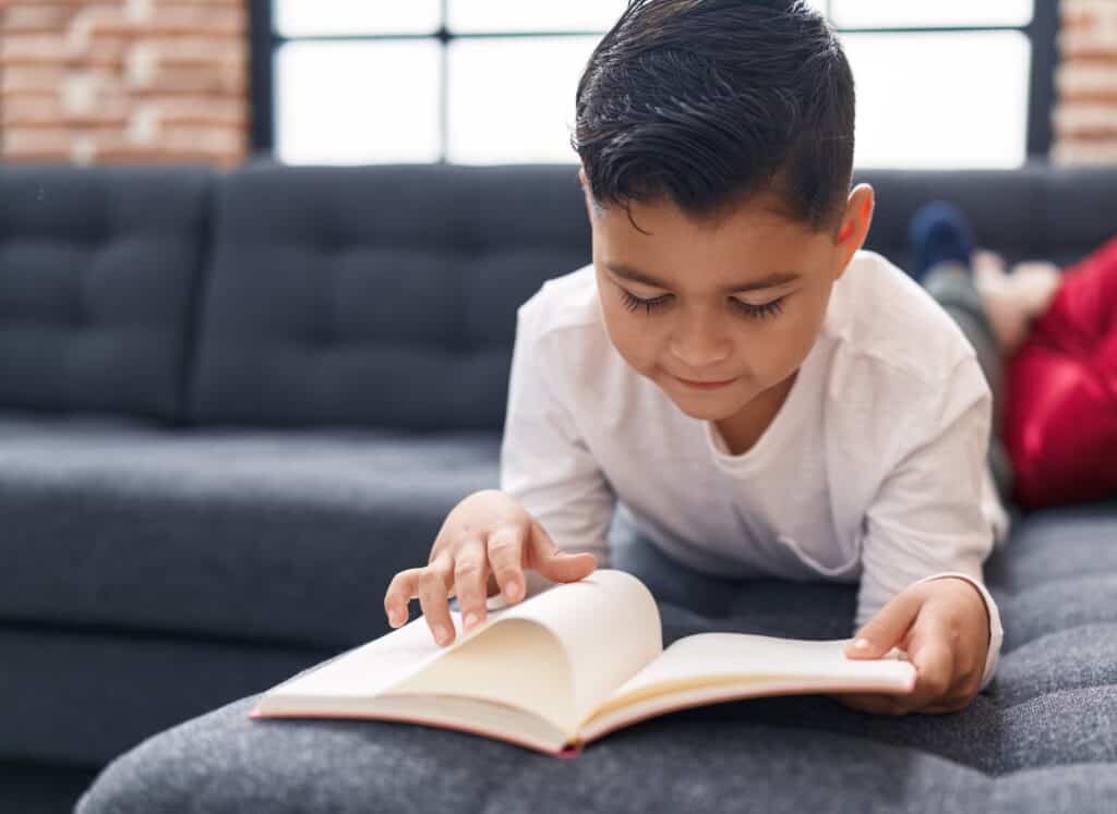 Little boy reading a book on the couch