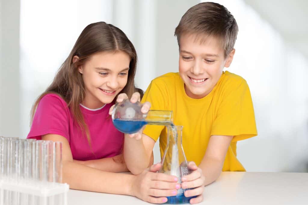Middle school students pouring blue liquid into a beaker