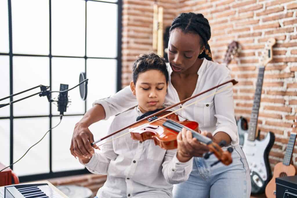 Woman teaches young boy how to play the violin