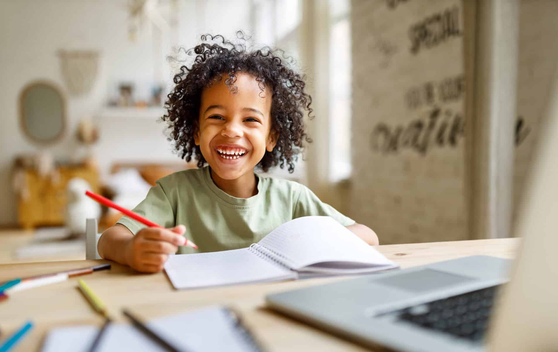 little boy smiling and writing in a notebook