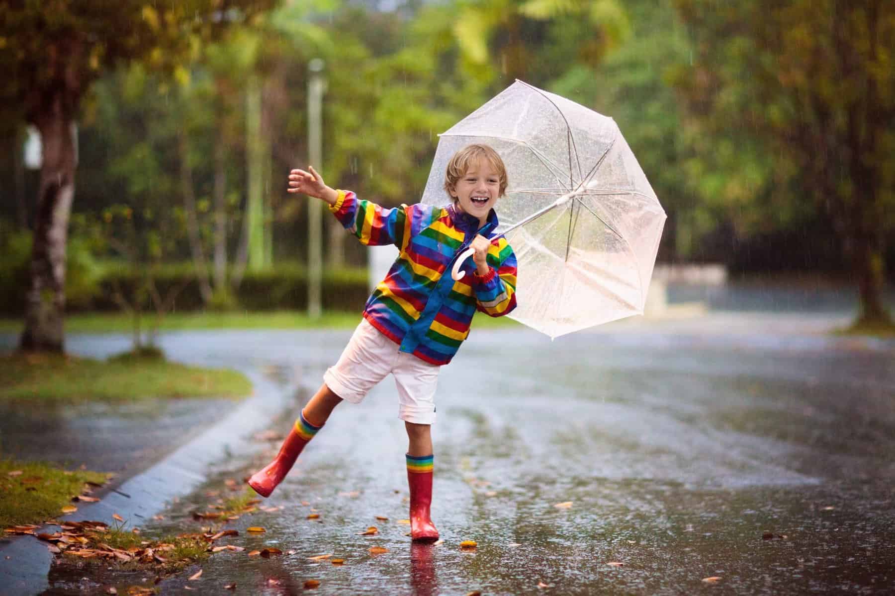 Child with umbrella playing in the rain